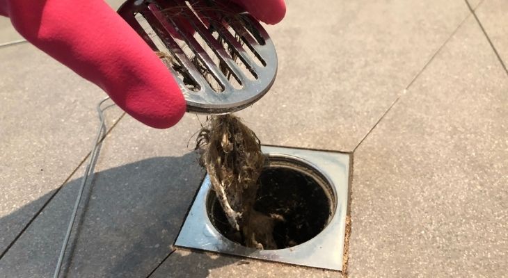Person unclogging a drain that's become blocked with hair